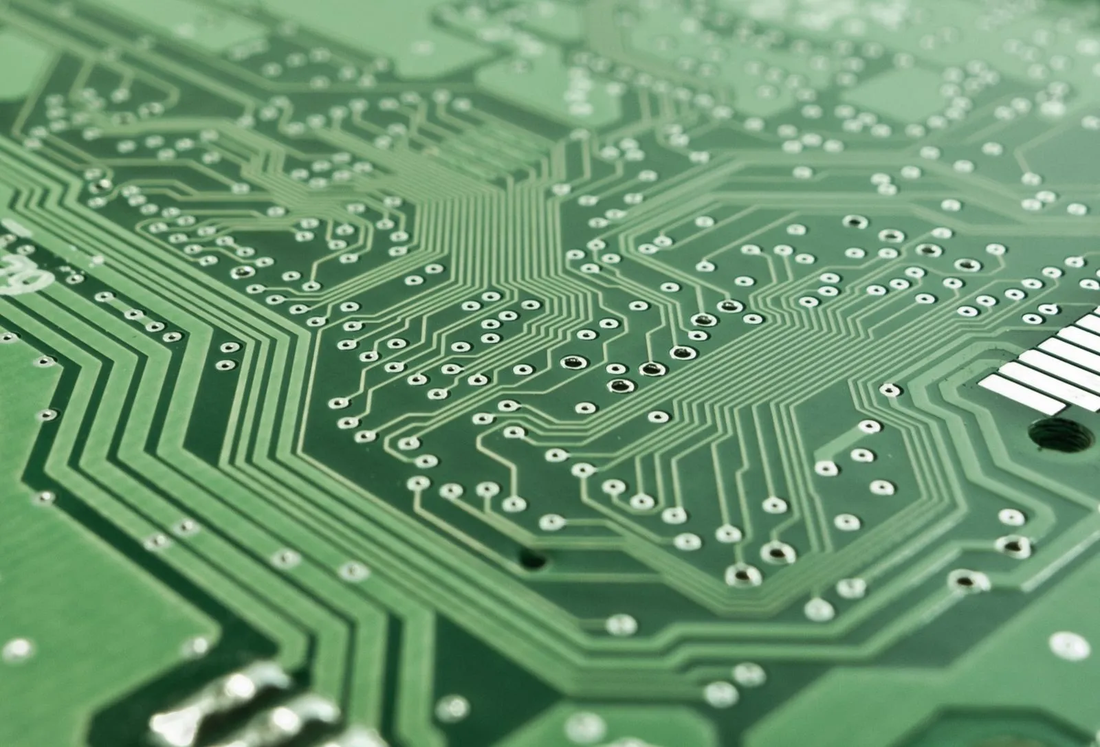 Detailed view of a green circuit board with complex patterns and pathways.